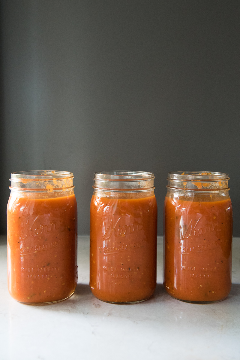 Slow cooker filled with simmering tomatoes, onions, and herbs, showing the rustic texture of homemade sauce.